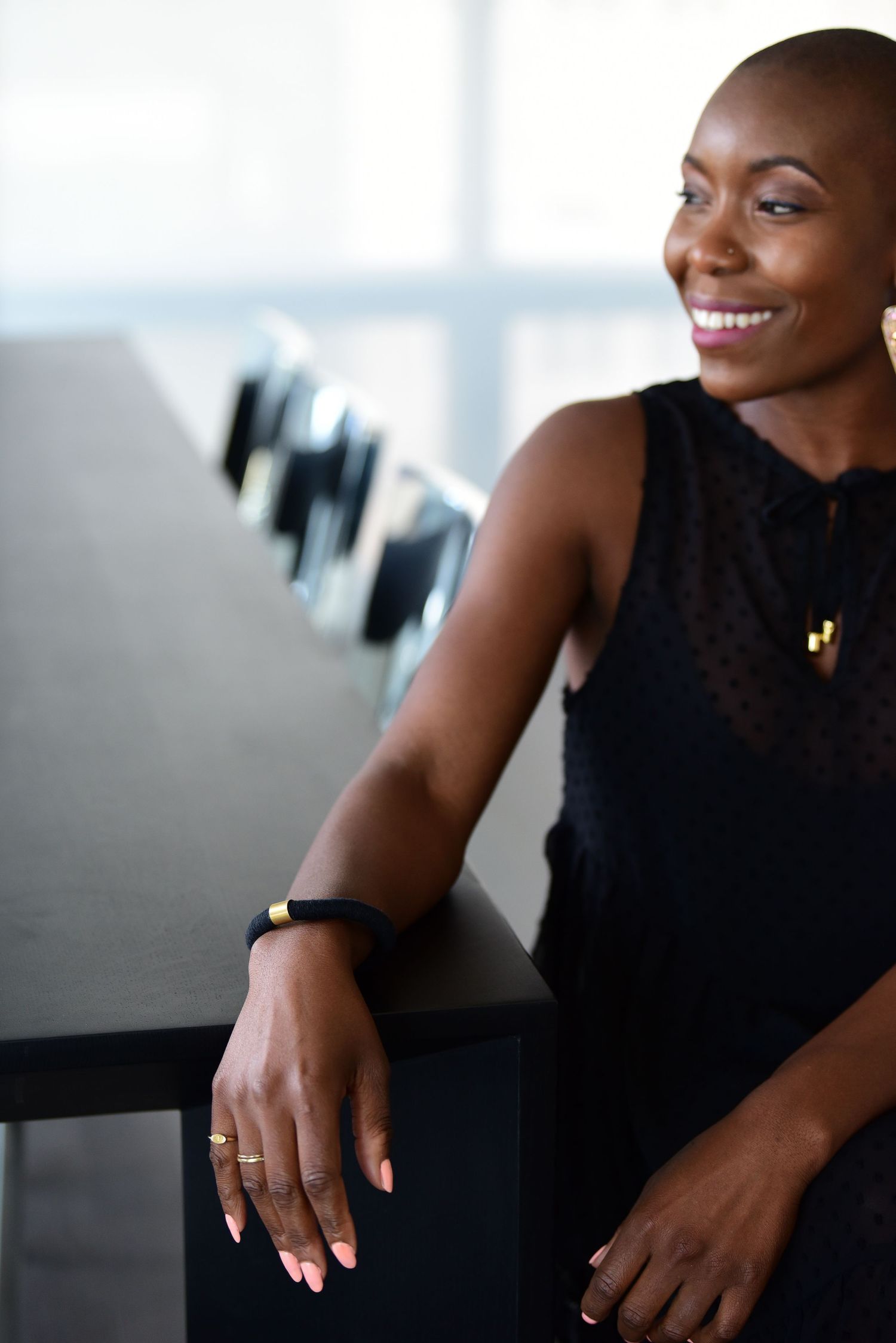 Professional wearing a sleek black sleeveless top in a modern office setting.