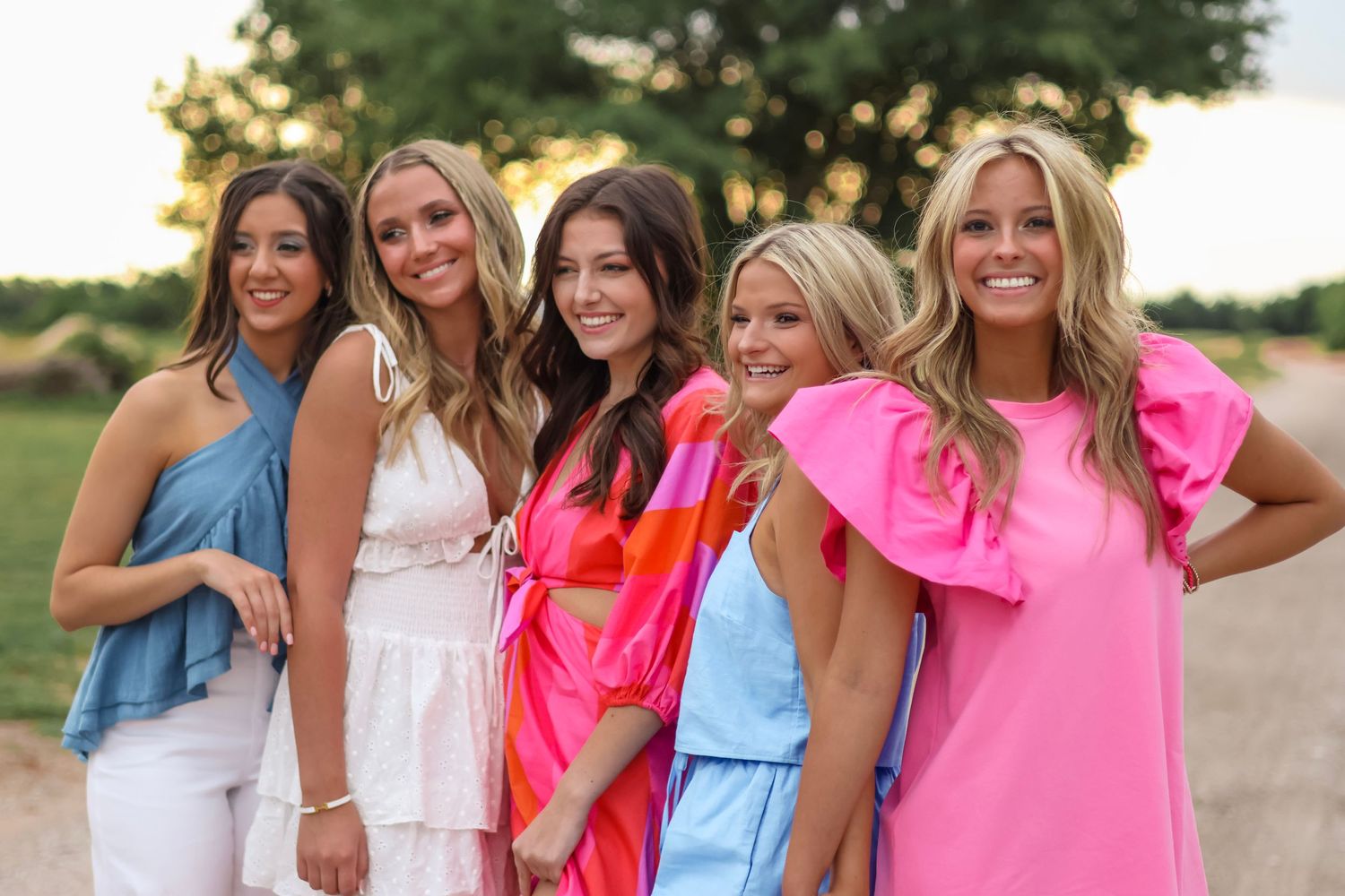 Group photo outdoors featuring summer dresses in pink, blue and white colors.