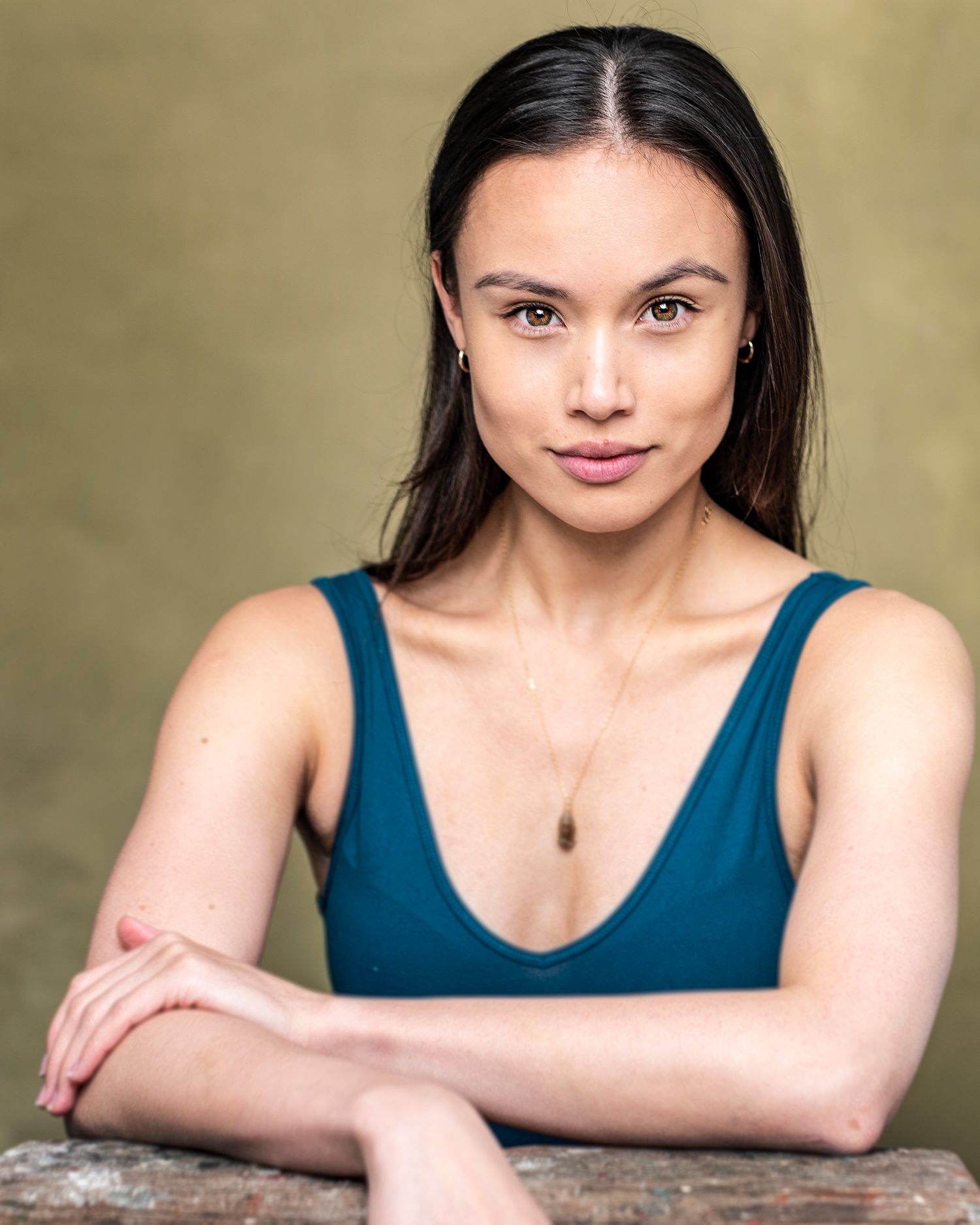 Professional studio portrait with dark background showing person in navy blue tank top.
