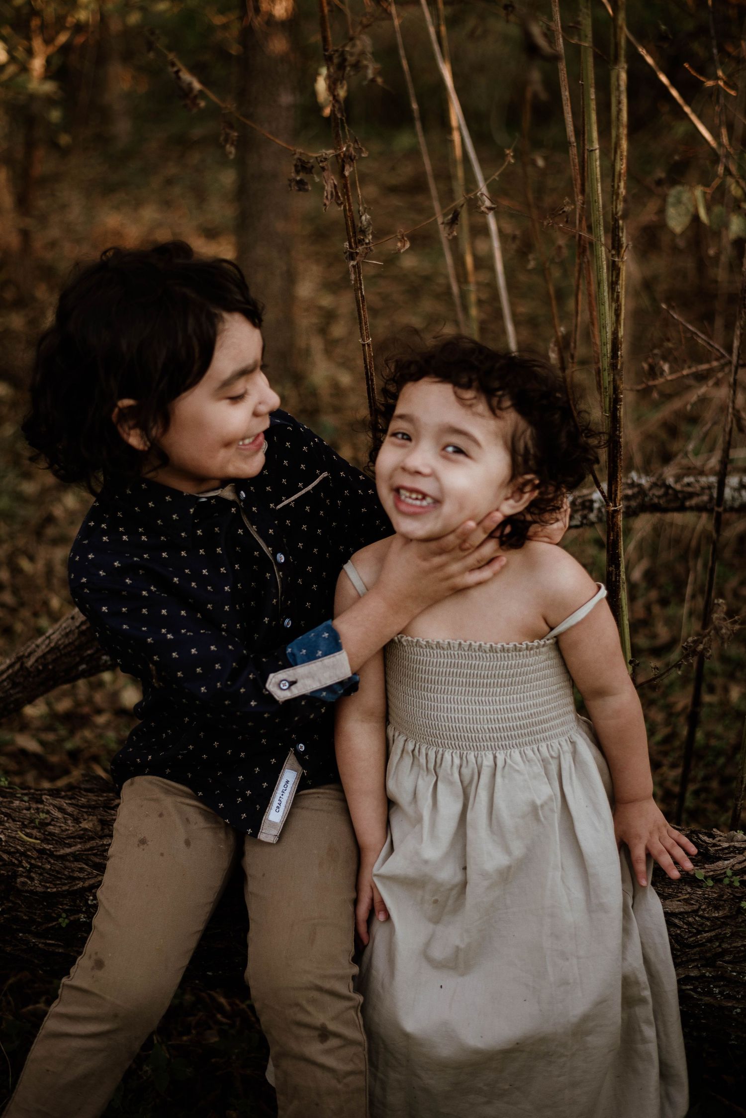 Two people sharing a joyful moment together in the woods with warm golden lighting.