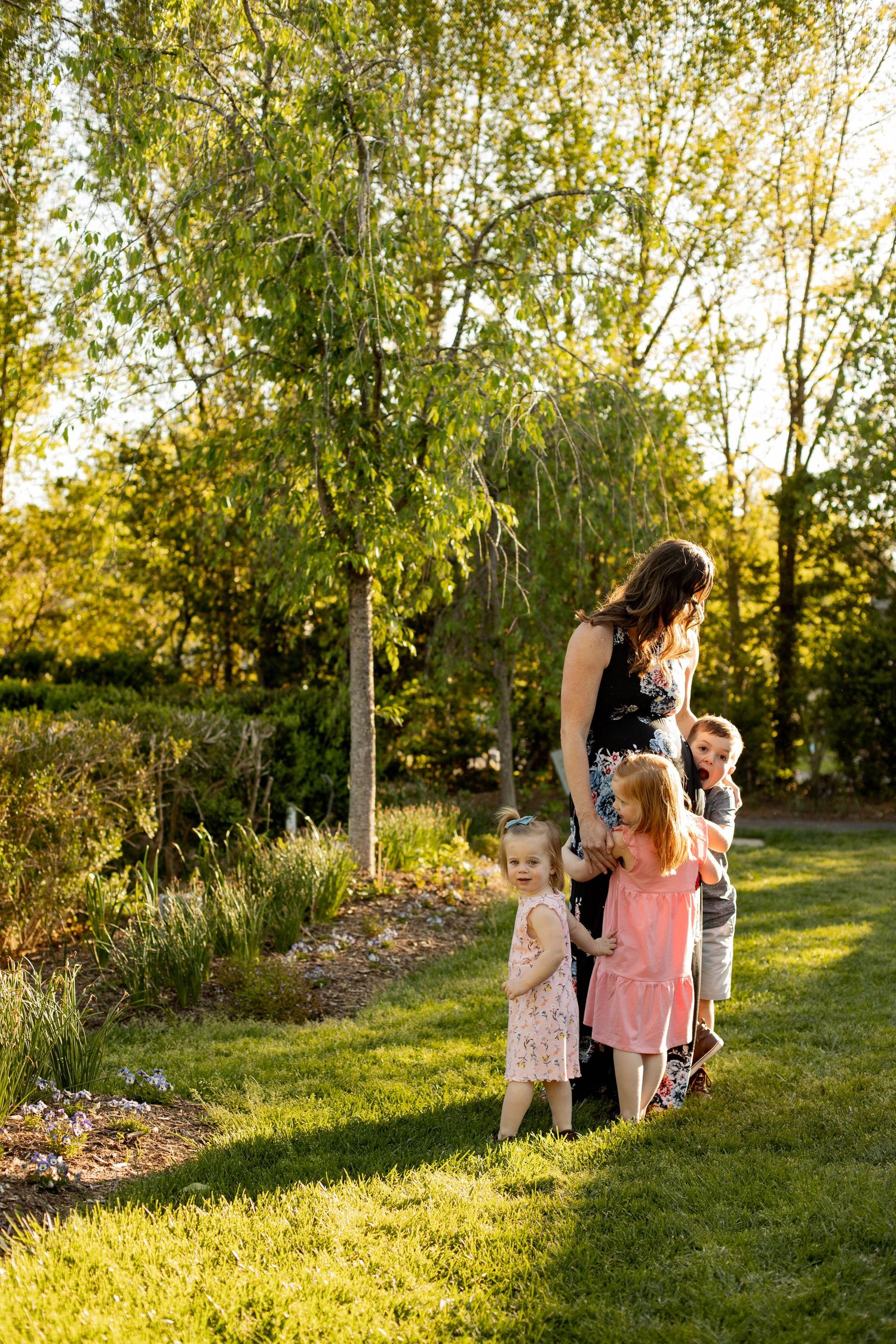 Children playing and laughing together in a sun-dappled garden setting.