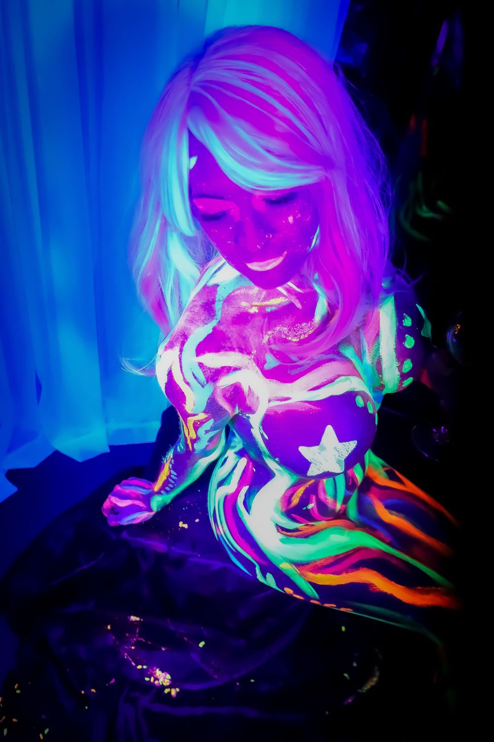 Colorful neon portrait with vibrant pink and blue lighting effects creating a psychedelic glow in a dark setting.