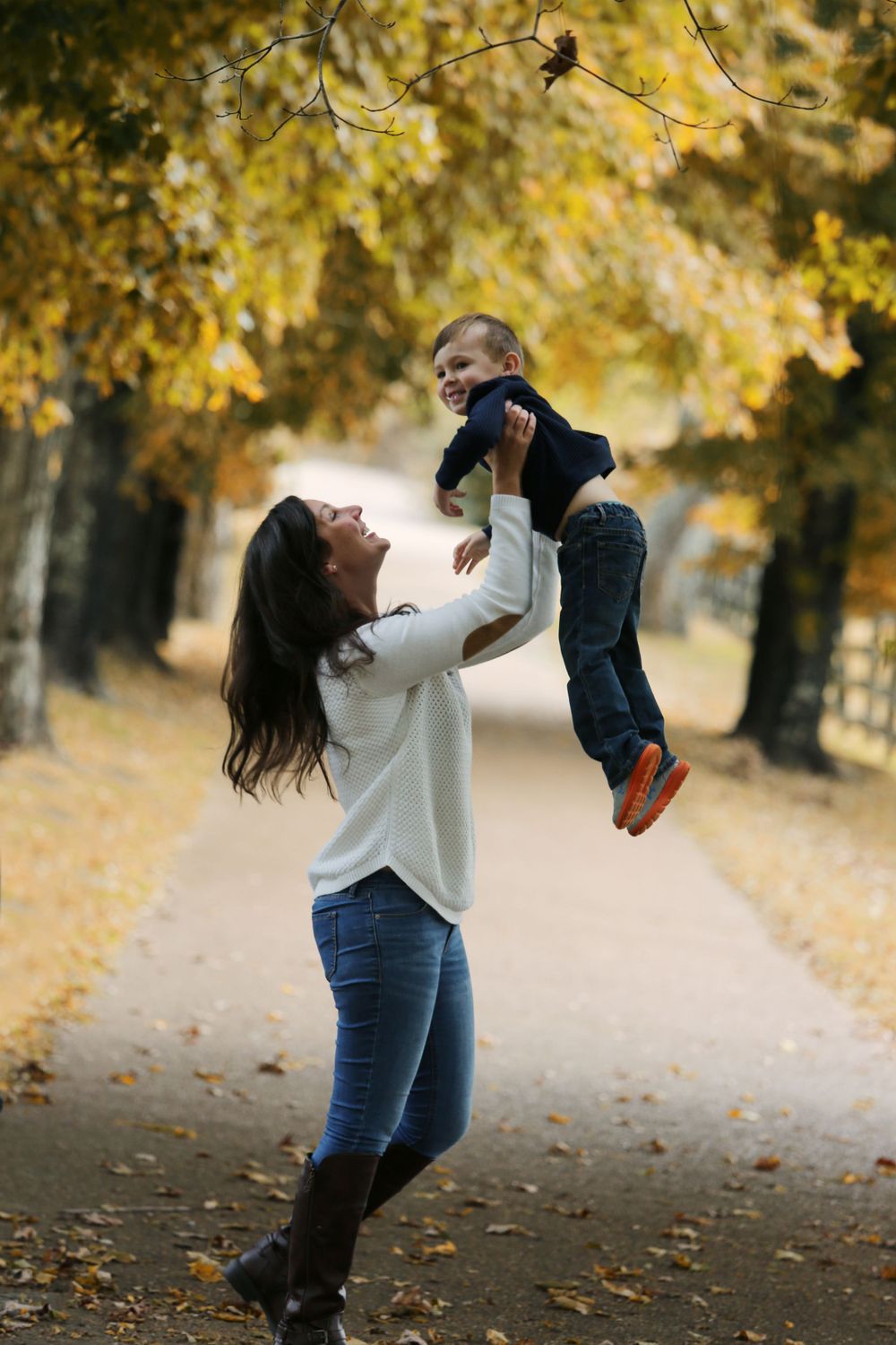 Joyful moment between parent and child playing in autumn park setting.