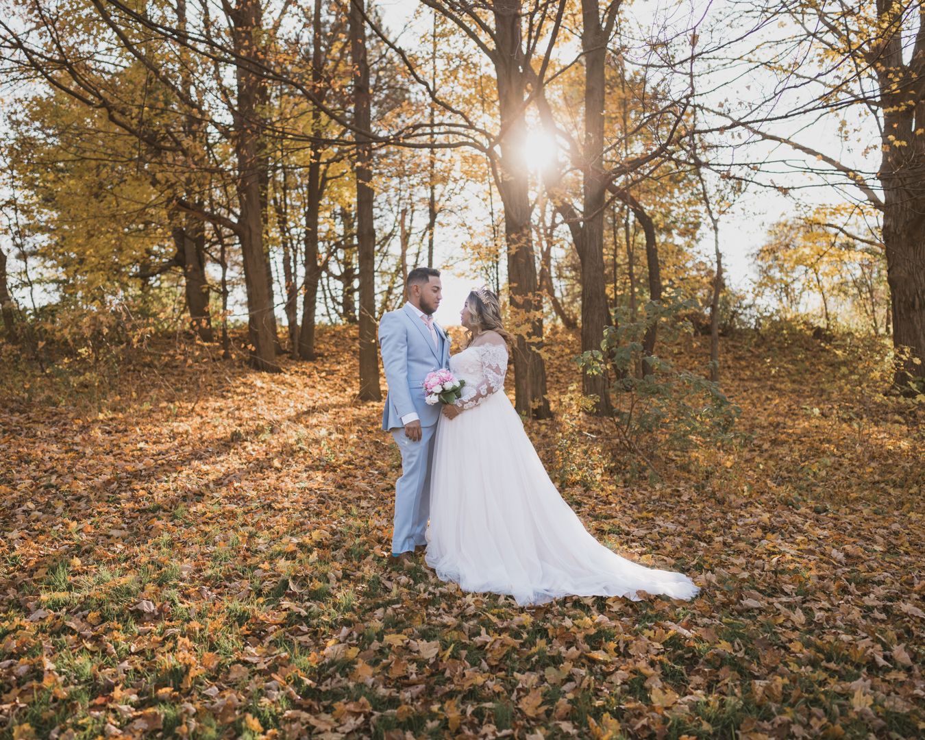 Groom and Bride standing in autumn leaves looking at eachother