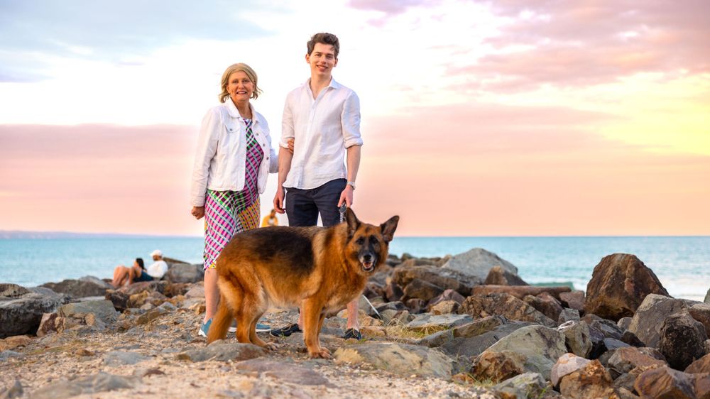 Mother and son with their dog at the Noosa spit during sunset golden hour. Very beautiful soft sunset colours in the background.