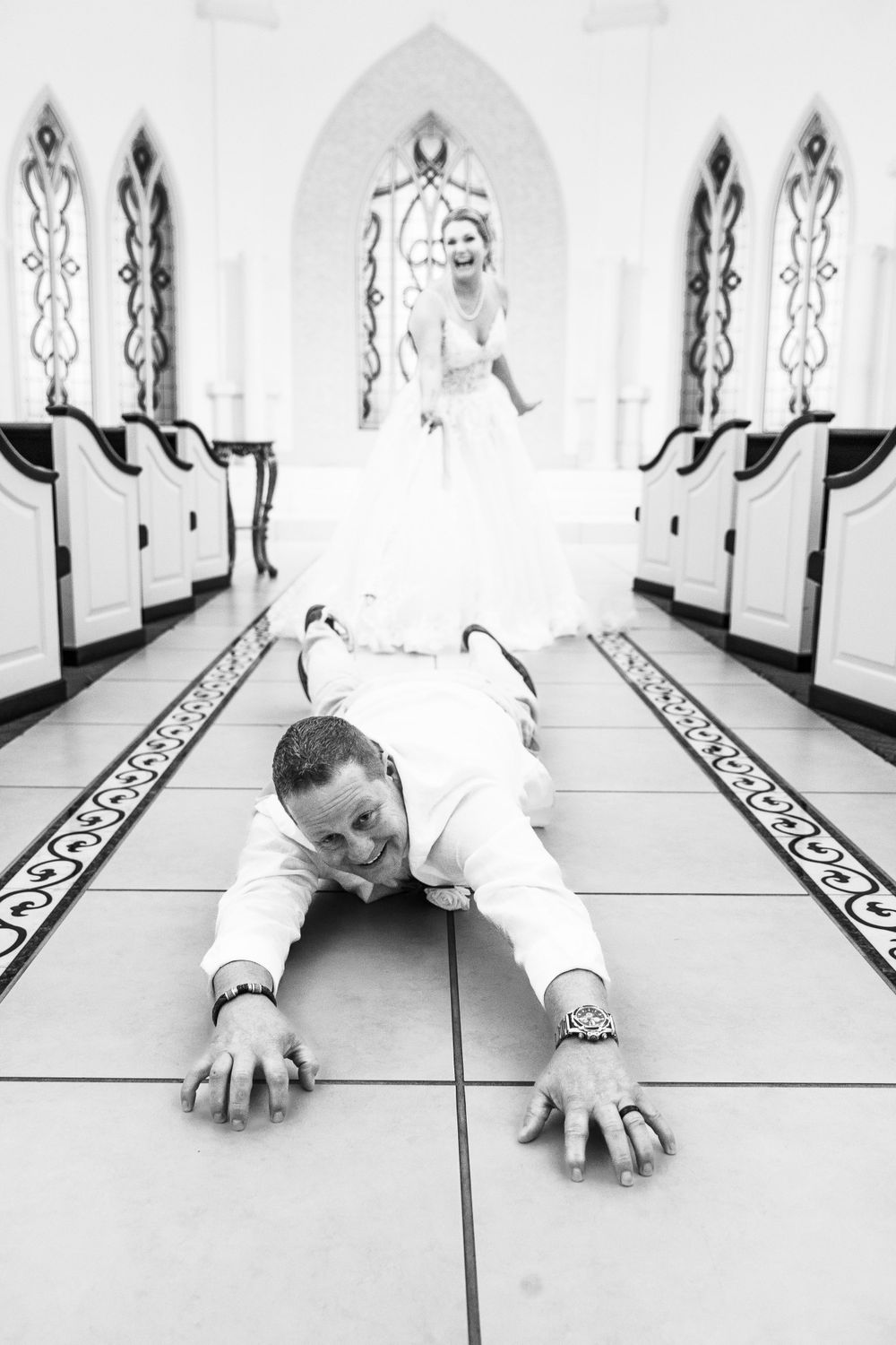 Artistic black and white photo of person lying on geometric tiled floor in formal wear.