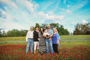 Extended family poses together in vibrant red poppy field on sunny day.