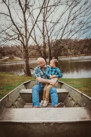 Two people sharing a tender moment in an old wooden boat by the lake.