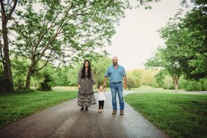 Family members stroll along tree-lined path during outdoor photo session.