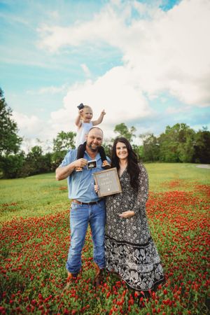 Family gathering in beautiful wildflower field filled with bright red poppies under blue sky.