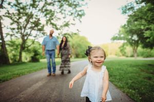 Family walking together on peaceful nature path surrounded by green trees.