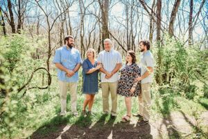 Candid group portrait showing joyful interactions in a sunlit forest setting.