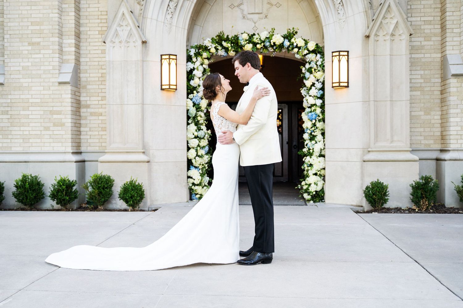 Bride and Groom facing each other in each others arms in front of the entry way to the ceremony site