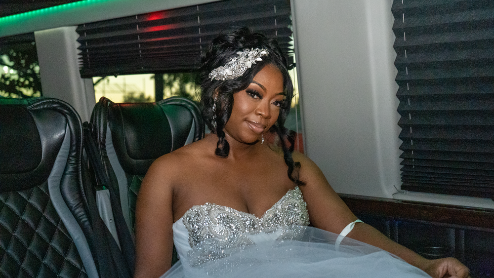Person in white embellished wedding dress sitting in luxury vehicle.