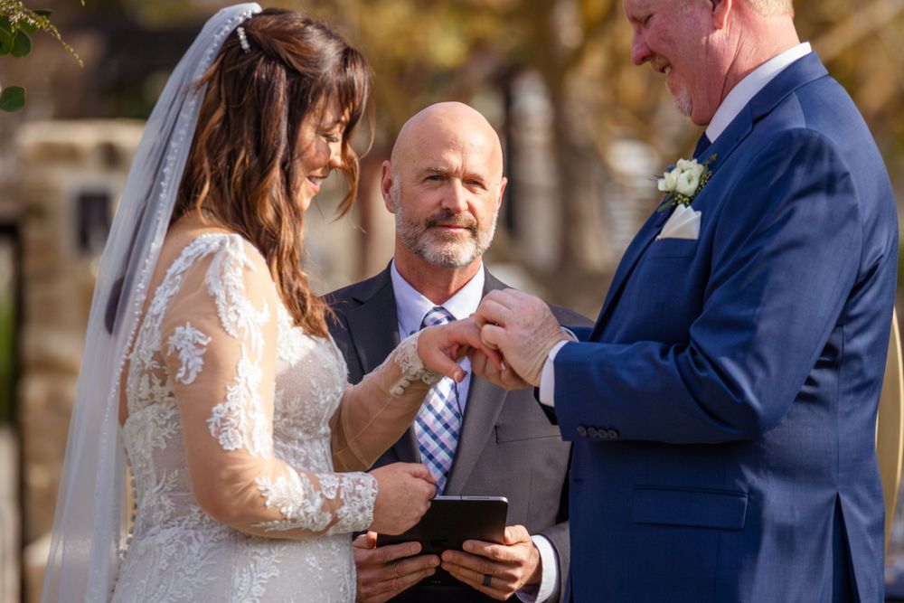 Wedding ceremony exchange of rings in outdoor garden setting.