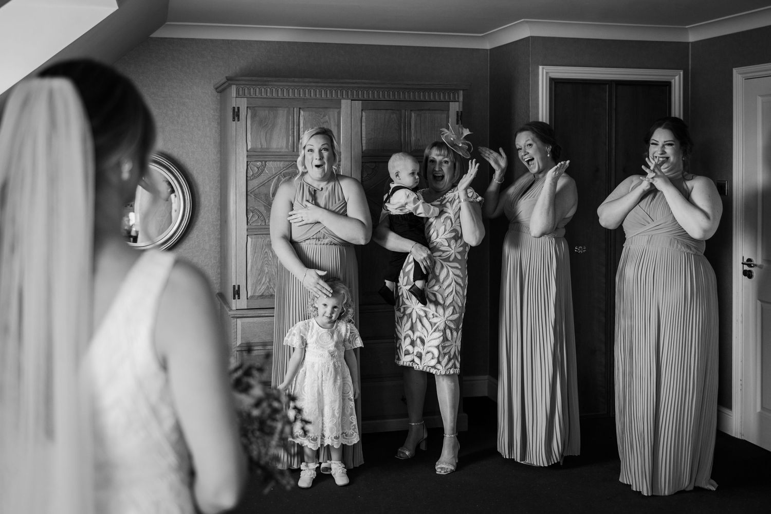Wedding party members react with excitement as they see the bride for the first time.