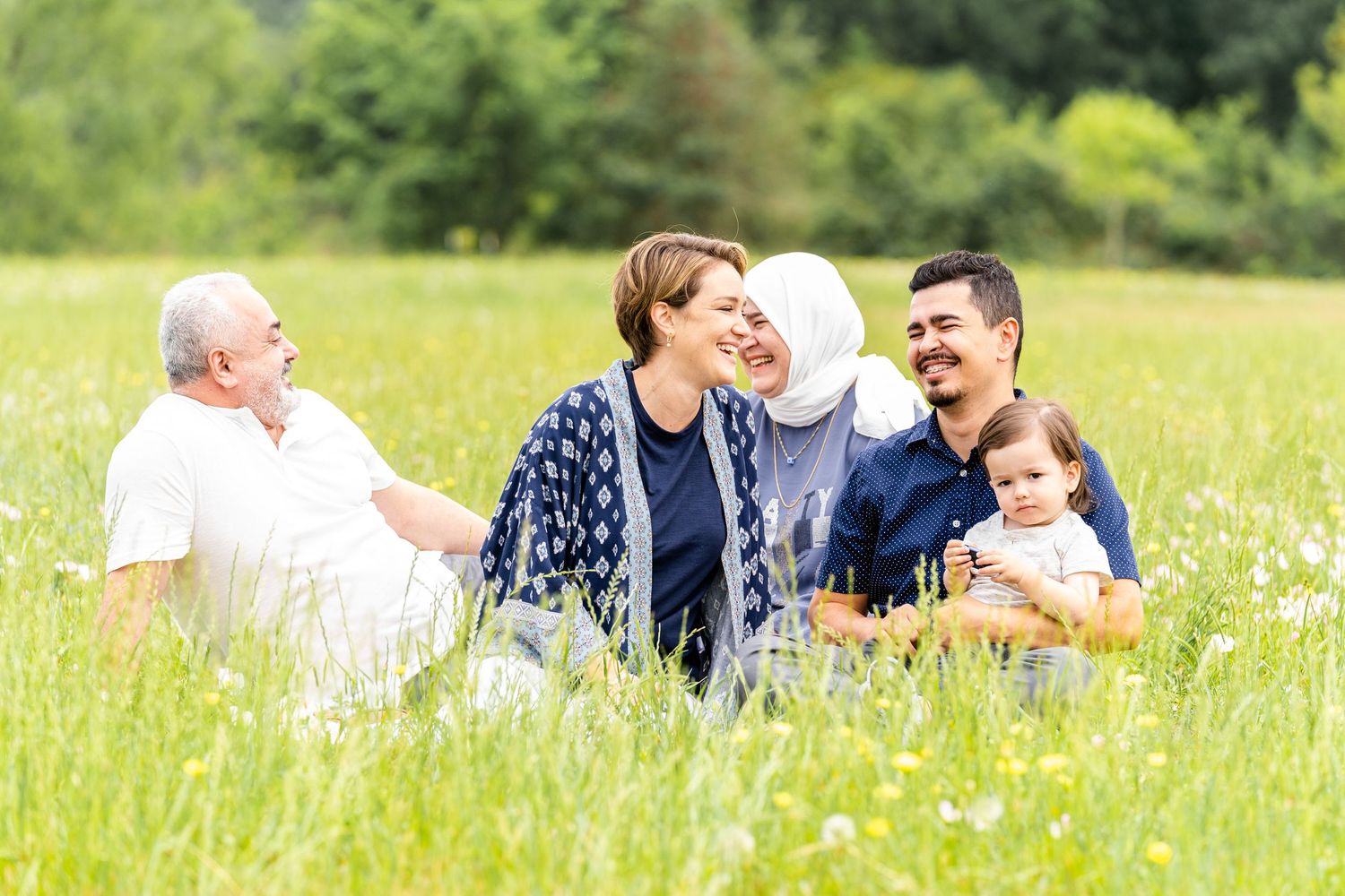 Family enjoying a sunny day together relaxing in a meadow filled with wildflowers.