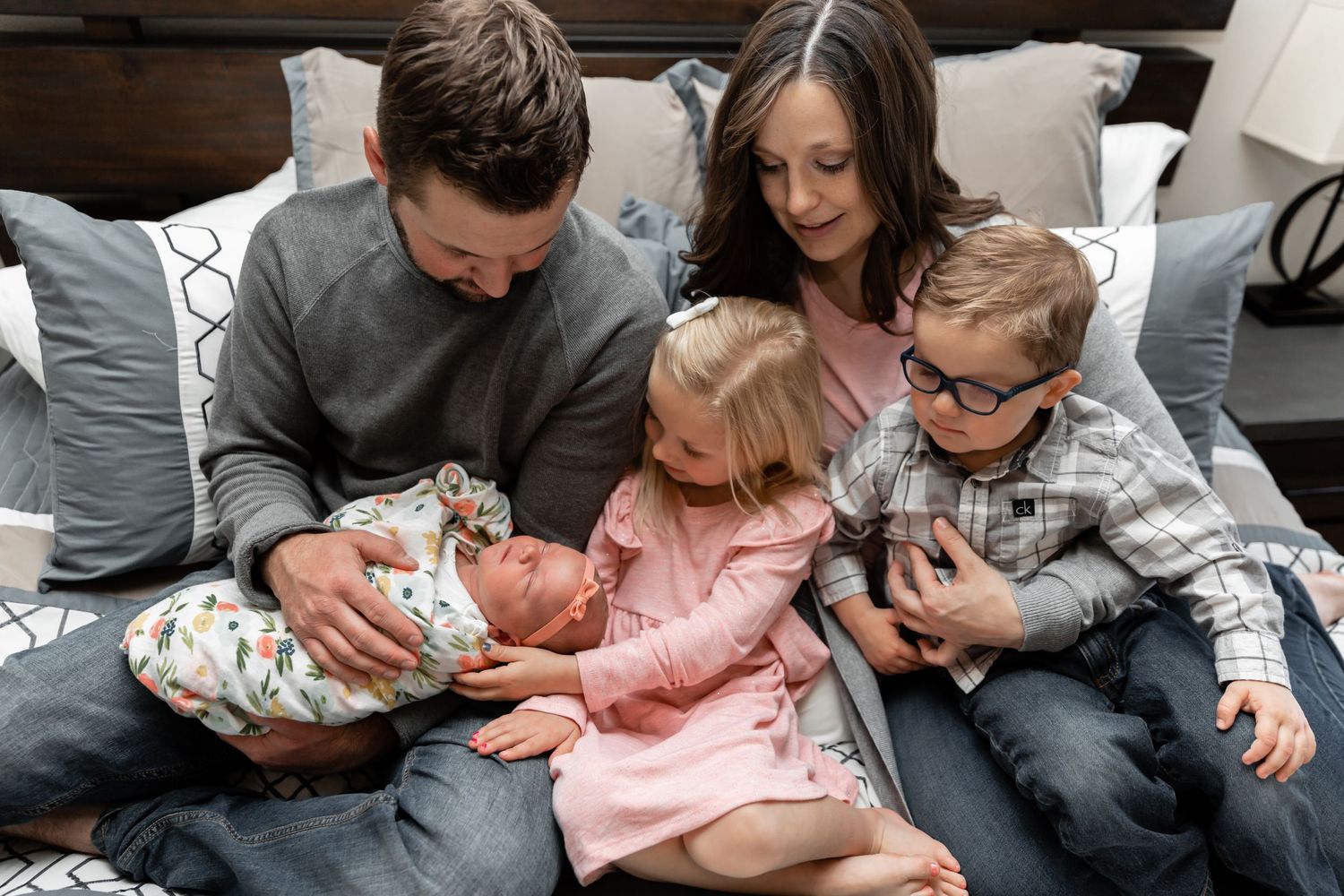 The Hall family holding and looking down at their new baby daughter for their in home family session.