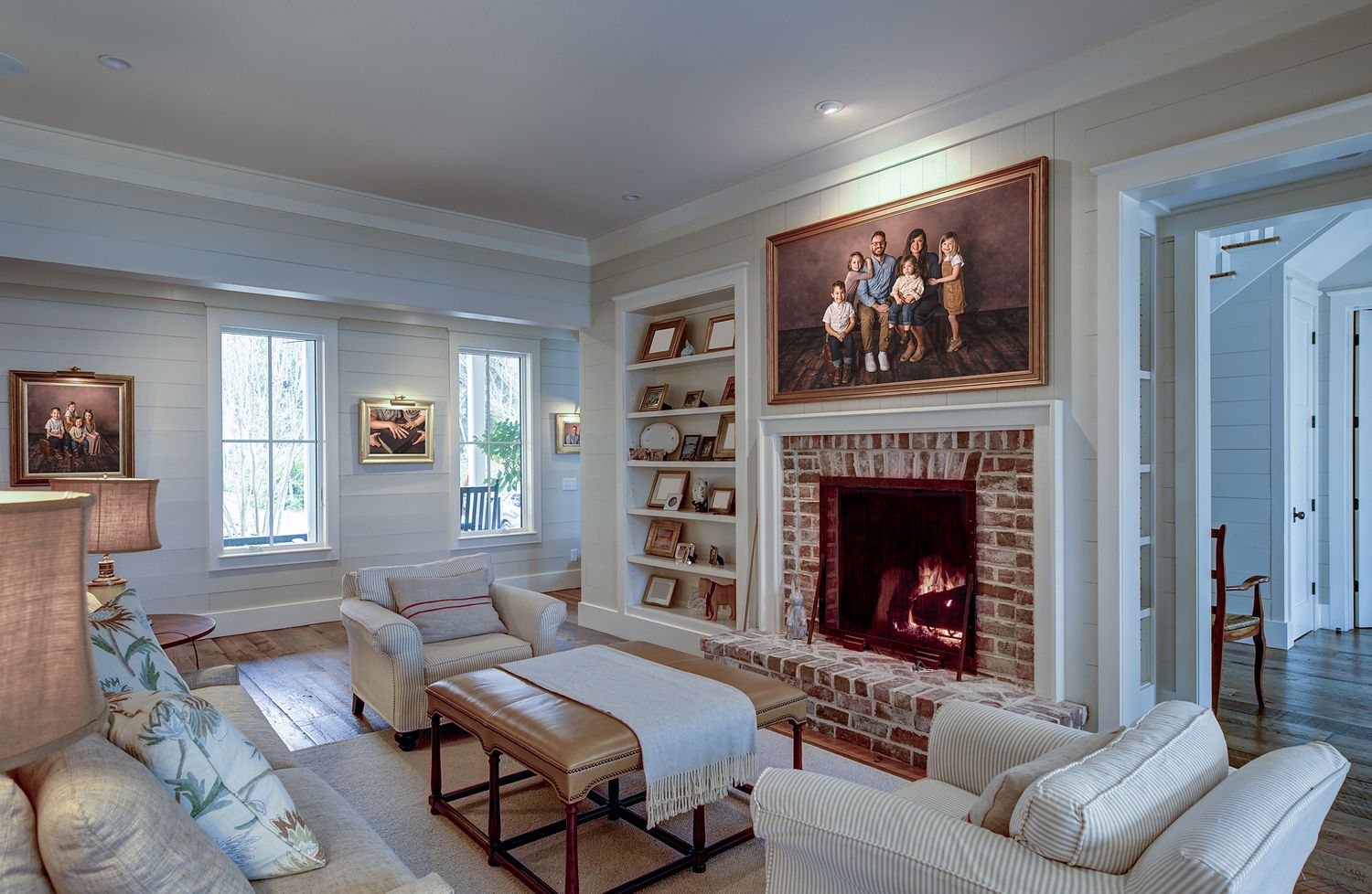 Living area in neutral colors with fireplace and portraits on walls.