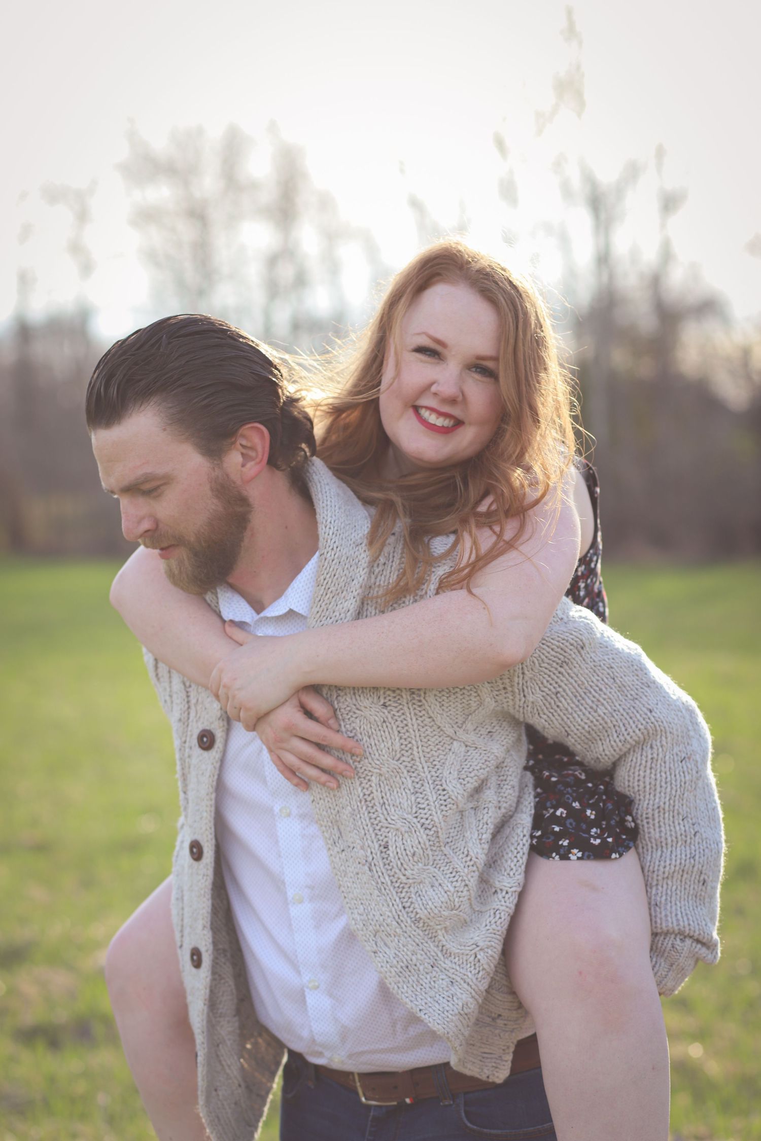 A playful piggyback ride moment captured in golden sunlight on a grassy field.