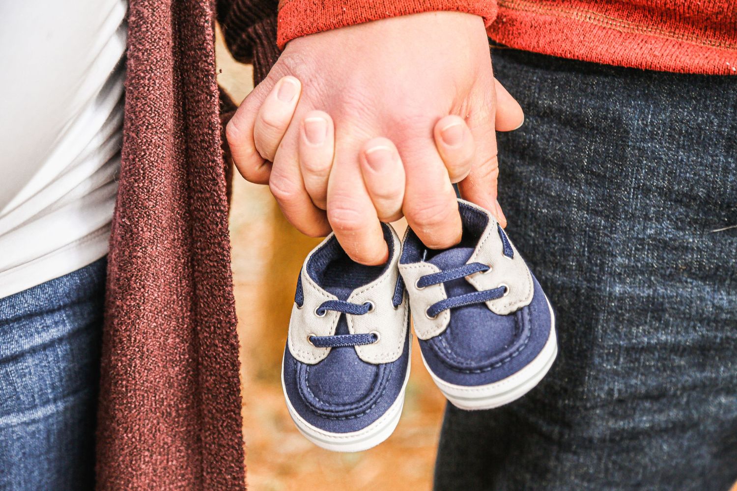 mom and dad hold hands and baby shoes maternity photo at Lime Hollow in Cortland NY