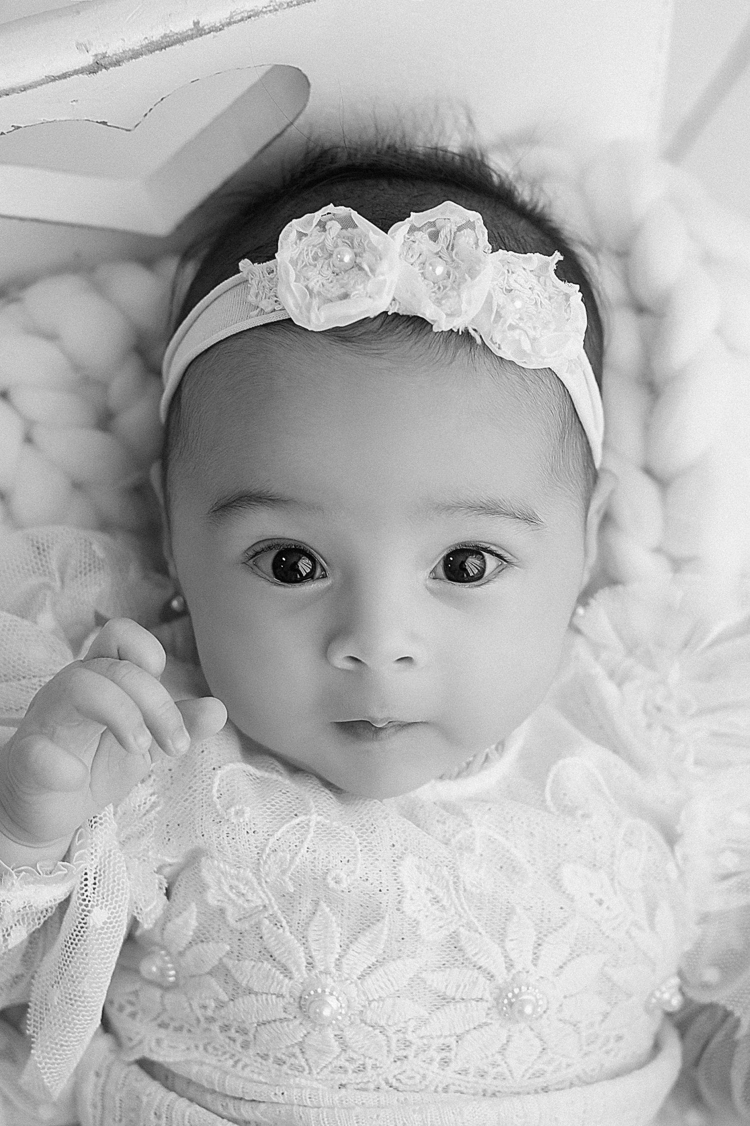 Sweet baby wearing delicate white lace dress and floral headband.