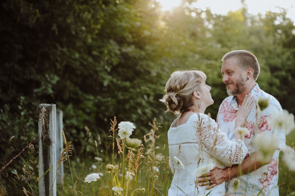 A couple covered in colorful powder playfully pose together during a vibrant outdoor engagement photo session.