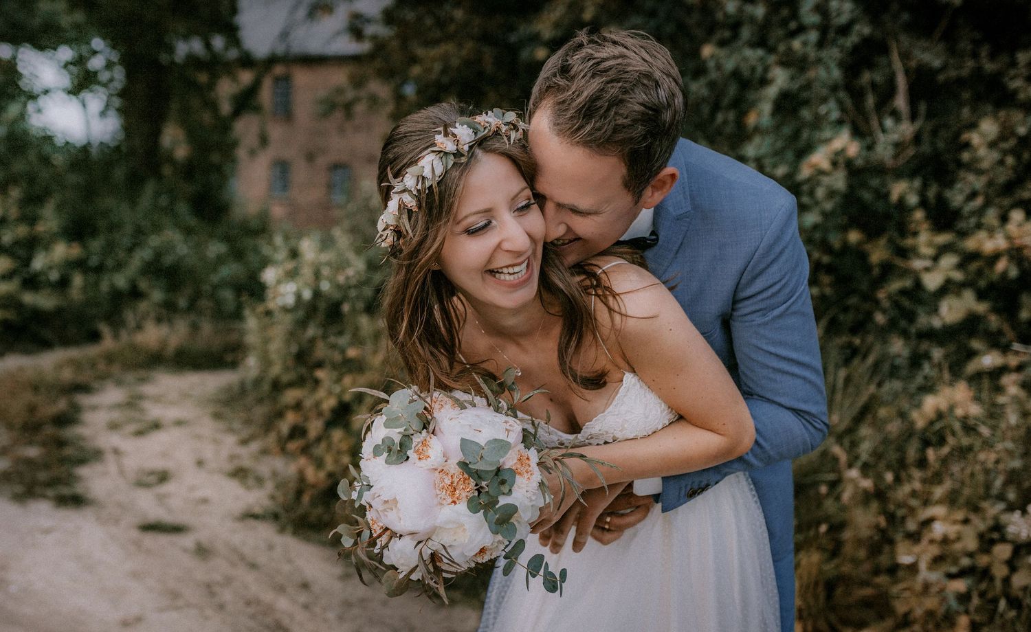 Joyful wedding couple sharing a tender moment outdoors with a elegant bouquet.
