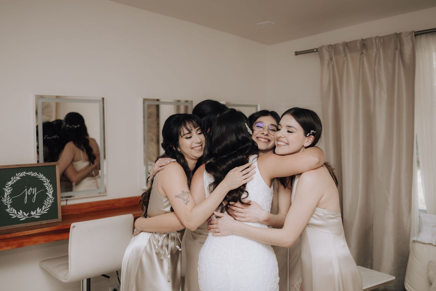 Bridesmaids sharing an emotional group hug during wedding preparations.