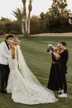 A wedding photographer captures a moment on a lush green golf course.