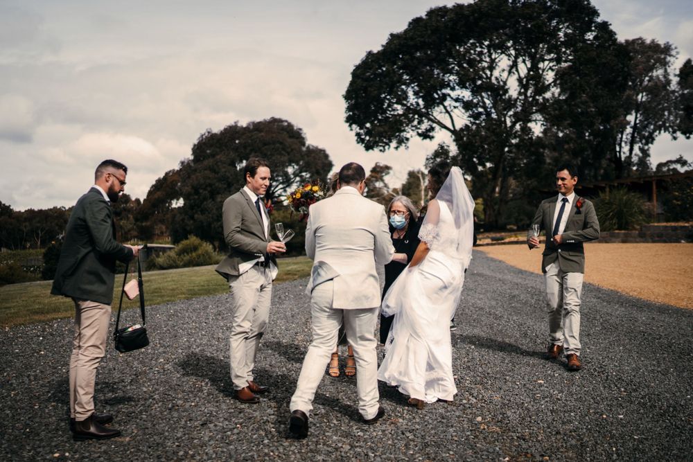 Wedding party poses for photos on a gravel path surrounded by trees and nature.
