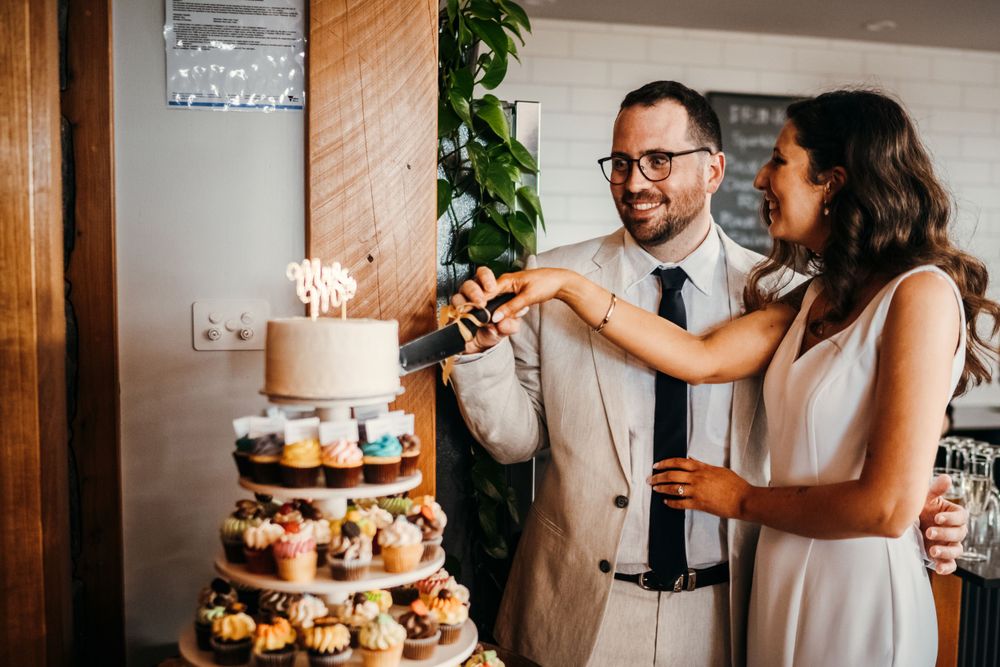 Couple shares an intimate moment next to a wedding cake and rustic wooden decor.