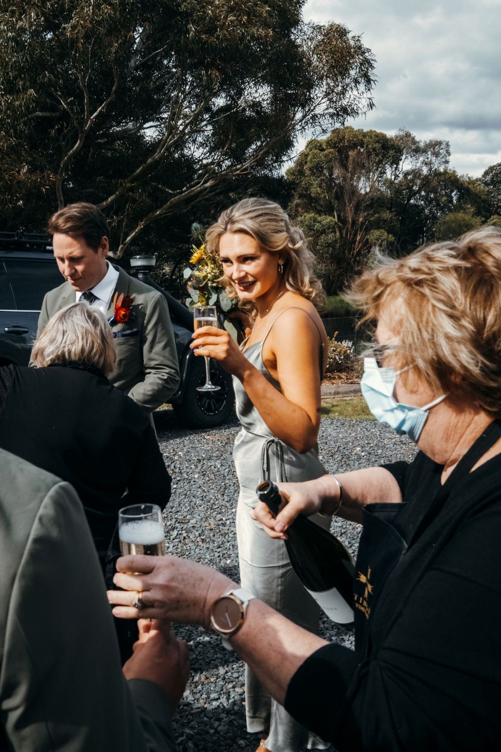 Wedding guests enjoying drinks during outdoor cocktail hour on gravel terrain.
