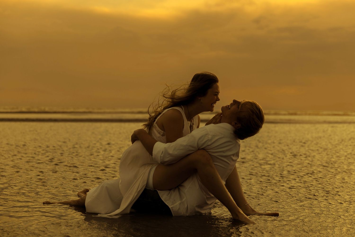 Warm sunset in a lake where couple is sitting with each other and laughing