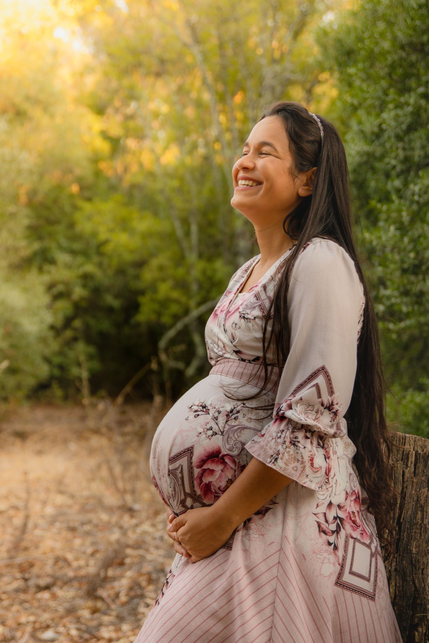 A maternity portrait series showing a pregnant woman in a floral dress against autumn foliage.