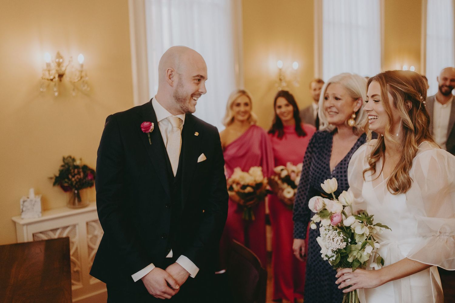 Wedding ceremony moment captured in elegant room with chandelier and floral accents.