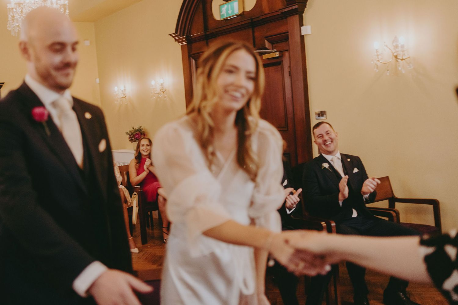 Wedding couple shares a lighthearted moment during their ceremony in an elegant yellow-walled room.