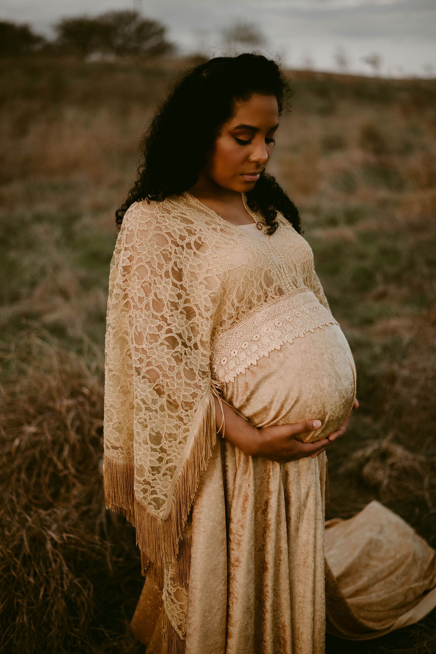 A close-up maternity photo featuring delicate cream lace details and flowing fabric.
