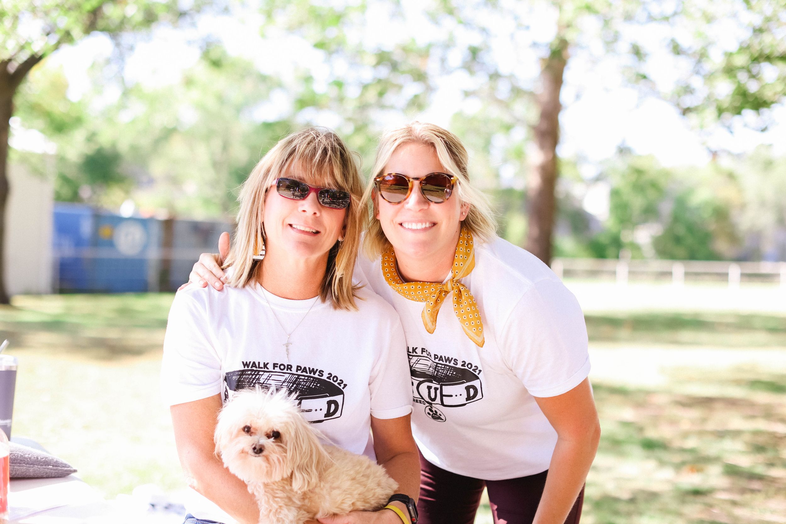 Group wearing matching t-shirts sitting together outdoors at a charity event.