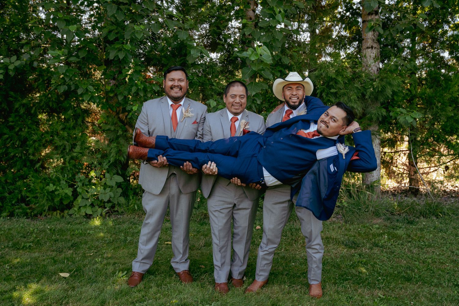 Fun groomsmen lifting a groom, groomsmen in cowboy hat, Oregon barn wedding.