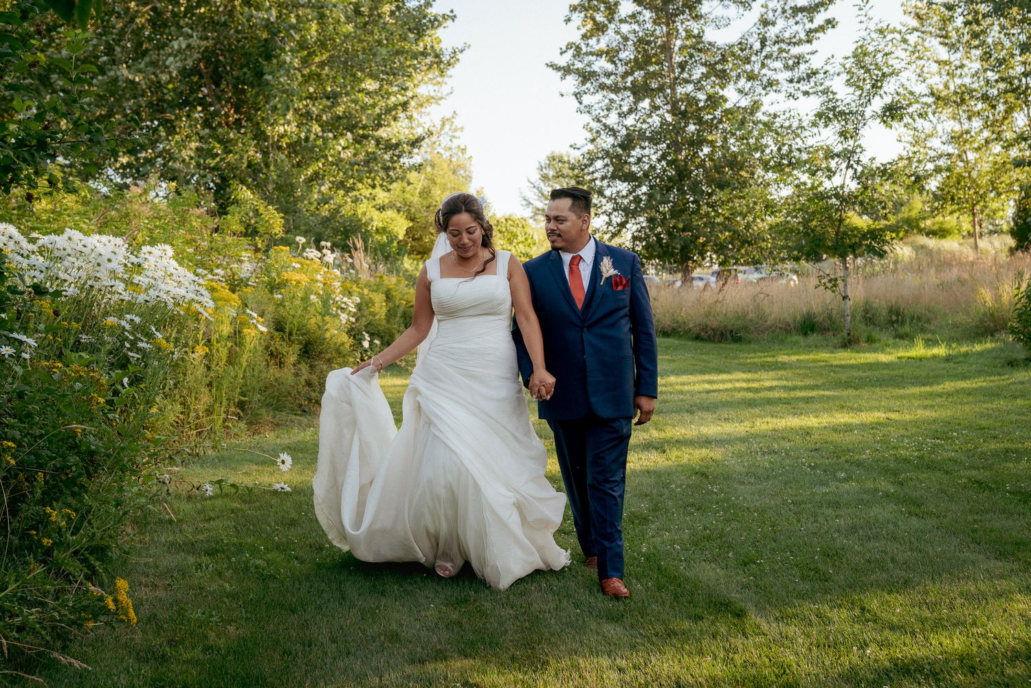 terracial couple walks grassy path together, late summer wedding.