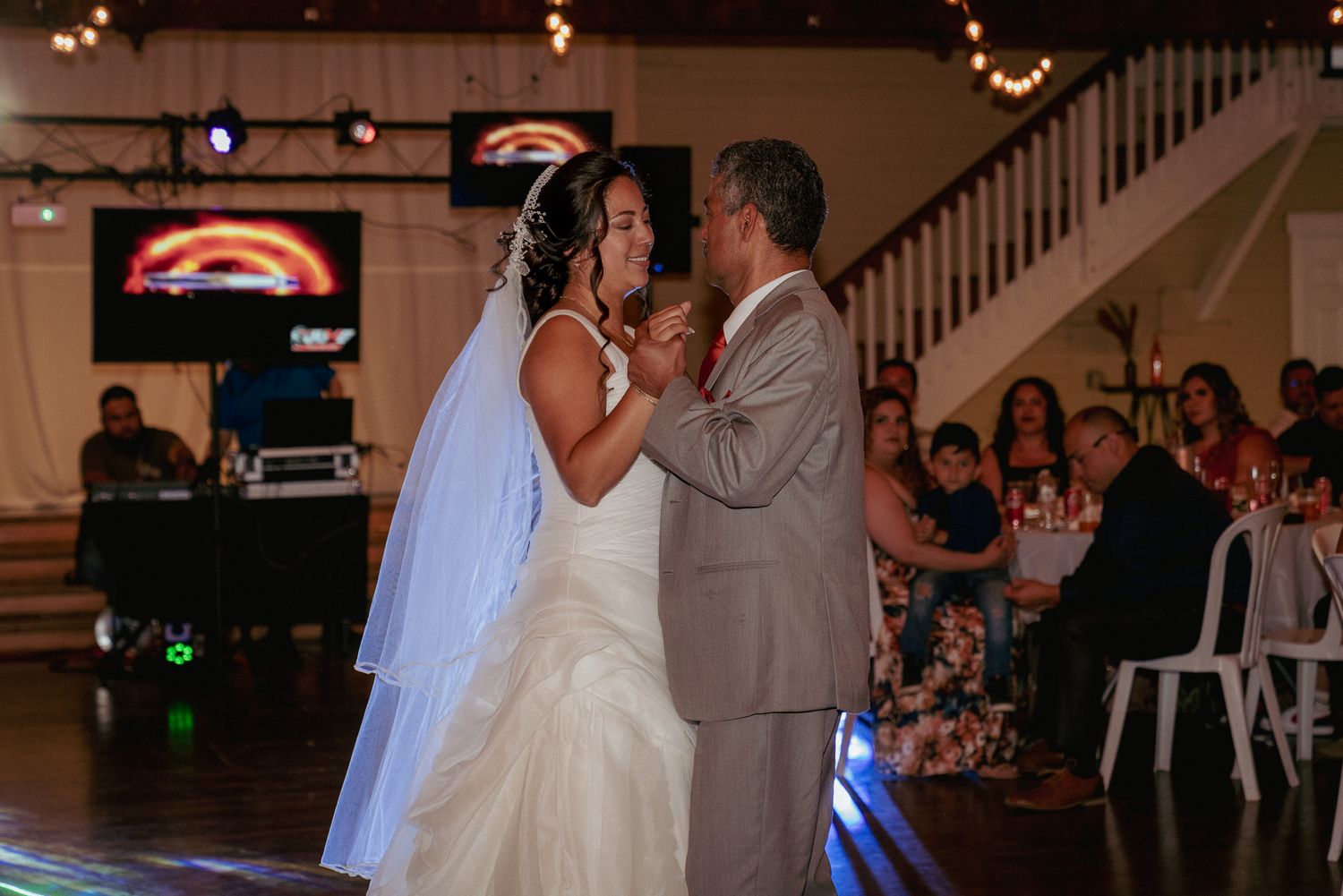 Couple shares first dance surrounded by guests, indoor Portland venue.