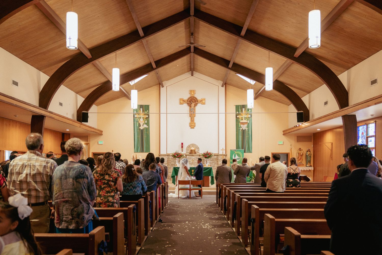 Wedding ceremony in Oregon church, guests seated with green banners.
