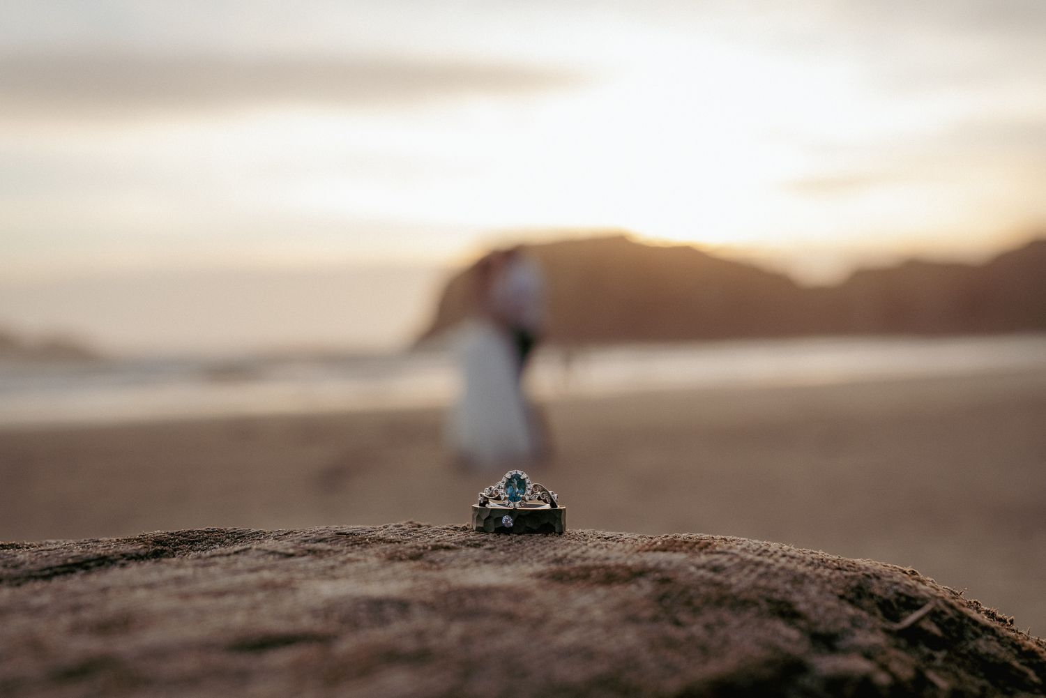 Engagement rings on beach rock at sunset, moody Oregon Coast elopement.