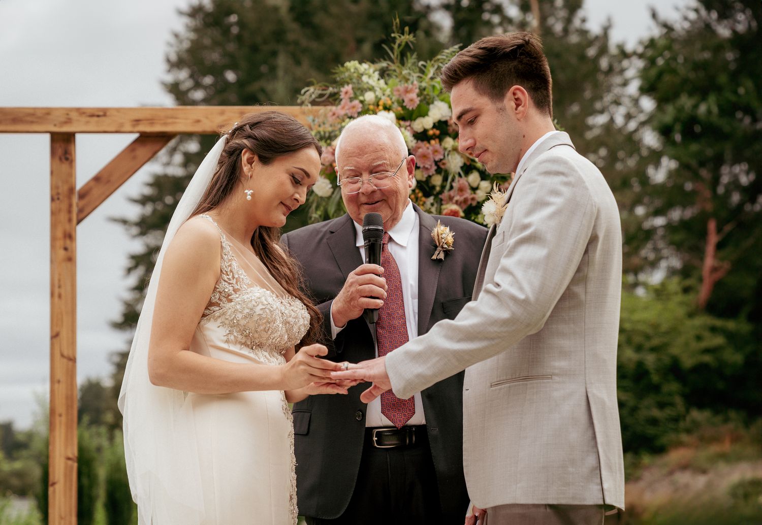 Bride and groom exchange vows with officiant, backyard Oregon ceremony.