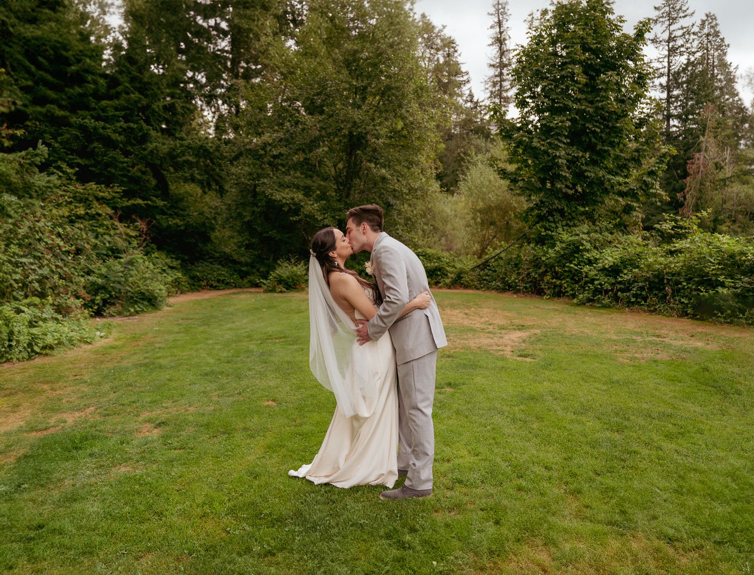Couple dips for kiss on golf course, lush PNW summer wedding.