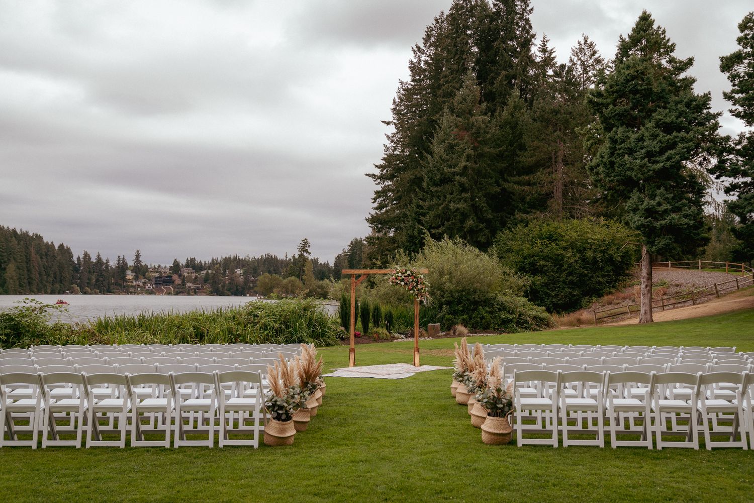 Outdoor wedding ceremony setup with wooden arbor, forest backdrop.
