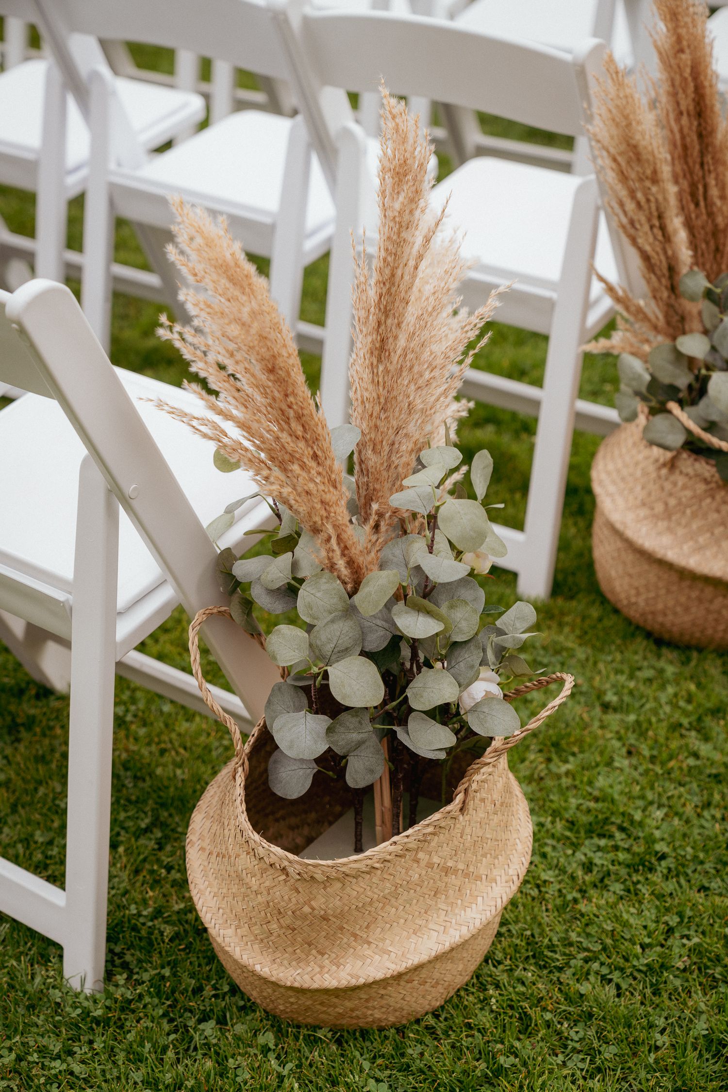 Pampas grass aisle decor in woven baskets, modern boho wedding vibes.