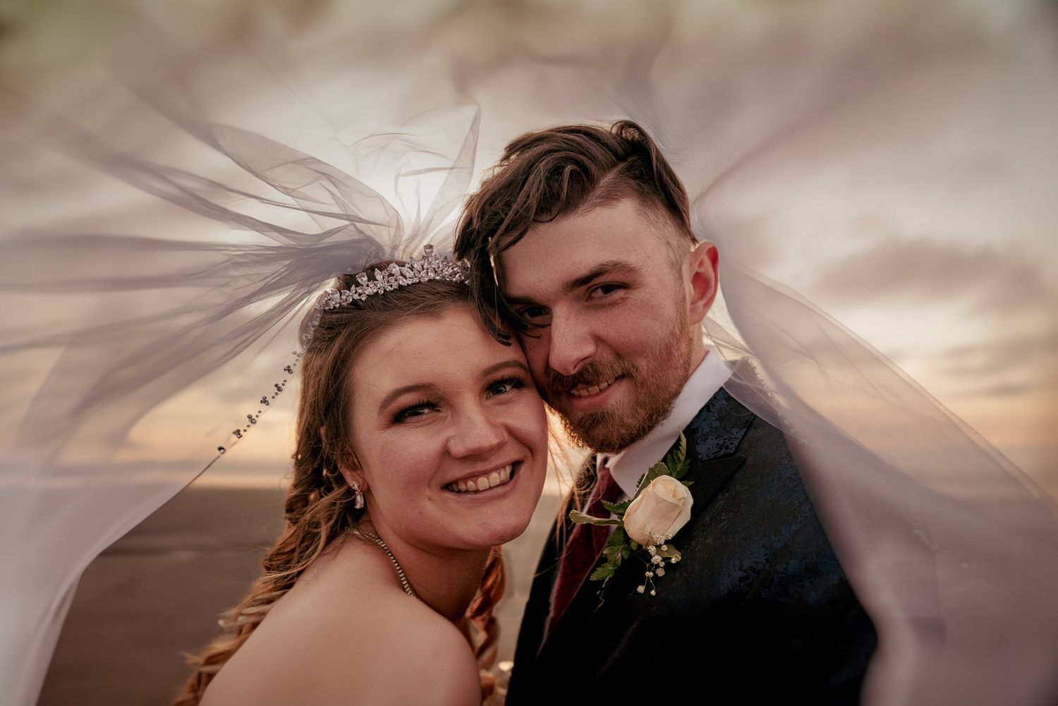 Close-up of smiling newlyweds under the veil, unique Oregon Coast style.
