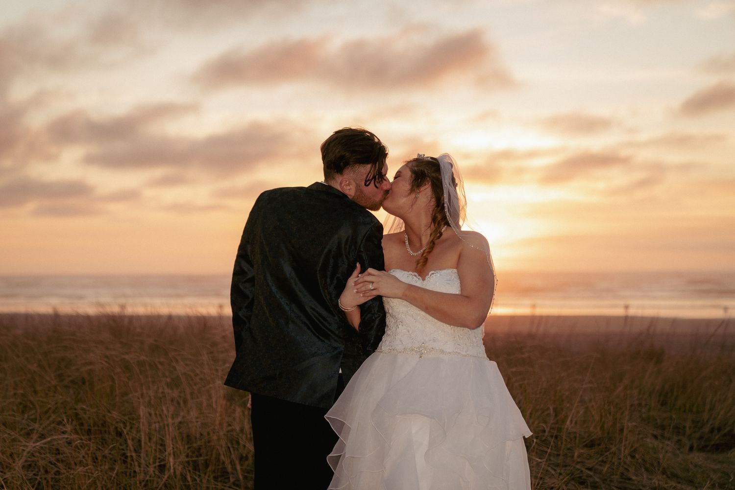 Moody sunset kiss in a field, alternative PNW wedding couple.